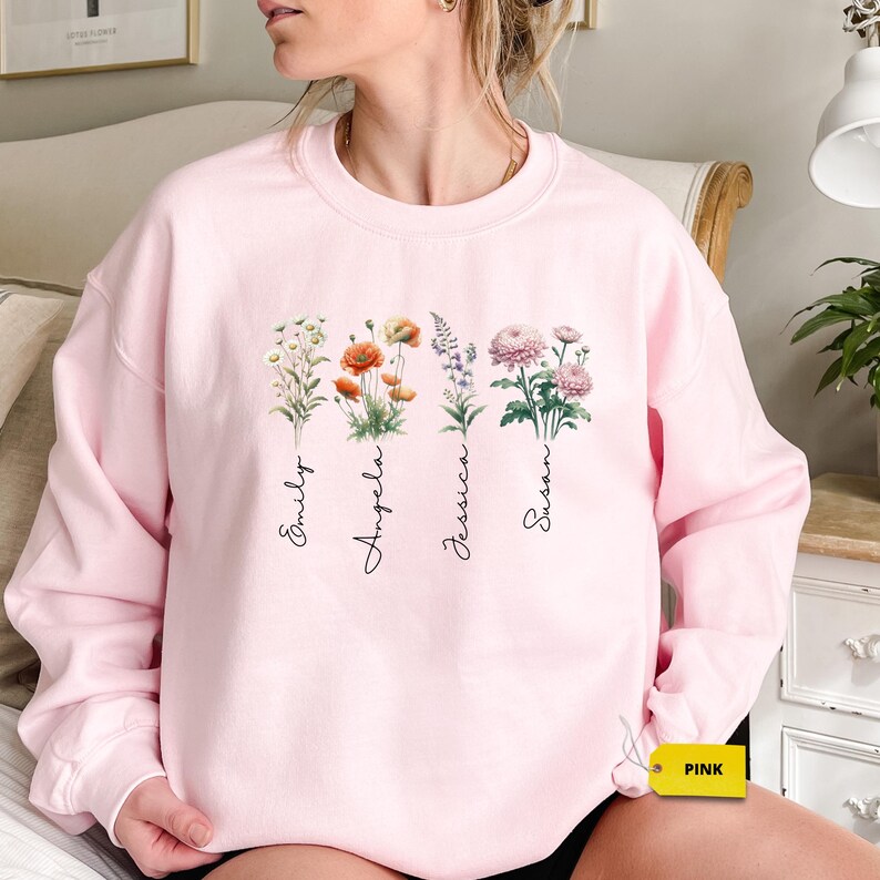 a woman sitting on a bed wearing a pink sweatshirt