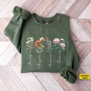 a green sweatshirt with flowers on it on a wooden floor