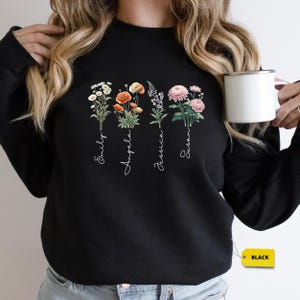 a woman is holding a coffee cup and wearing a black sweatshirt