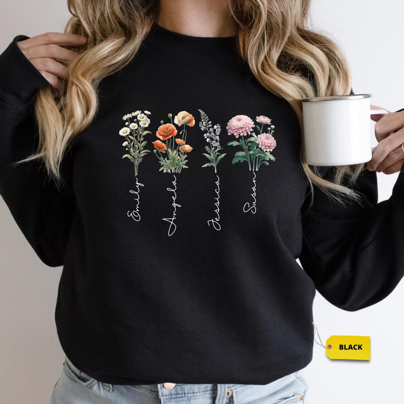 a woman is holding a coffee cup and wearing a black sweatshirt