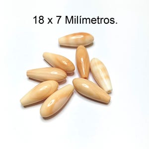 Può includere: Un gruppo di otto perline ovali di colore marrone chiaro con un motivo a spirale bianco. Le perline misurano 18 x 7 millimetri.