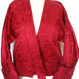 May include: A red silk kimono with a floral pattern. The kimono has long sleeves and a wide collar.