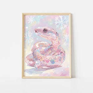 Könnte beinhalten: Ein gerahmter Kunstdruck mit einer pastellfarbenen Schlange mit einem gesprenkelten Muster. Die Schlange ist in Rosa-, Lila- und Blautönen gemalt, mit Schneeflocken-Akzenten im Hintergrund. Das Kunstwerk hat einen skurrilen, illustrativen Stil.