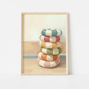 May include: A framed print featuring a stack of six colorful, checkered life preservers. The life rings are in shades of blue, red, yellow, green, orange, and pink, with white accents. The background has a beachy, pastel color palette.