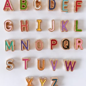 Puede incluir: Un conjunto de 26 cuentas de letras del alfabeto de color dorado con esmalte de colores. Cada letra est&aacute; hecha individualmente y presenta un color diferente.