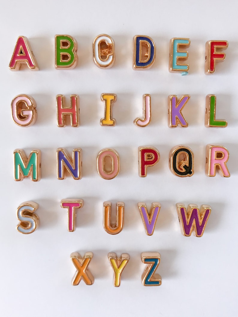 Puede incluir: Un conjunto de 26 cuentas de letras del alfabeto de color dorado con esmalte de colores. Cada letra est&aacute; hecha individualmente y presenta un color diferente.