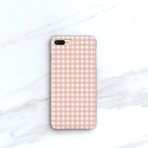 Pu&ograve; includere: Custodia per telefono con motivo a quadri rosa e bianchi. La custodia rettangolare ha un'apertura per l'obiettivo della fotocamera. Lo sfondo &egrave; una superficie di marmo bianco.