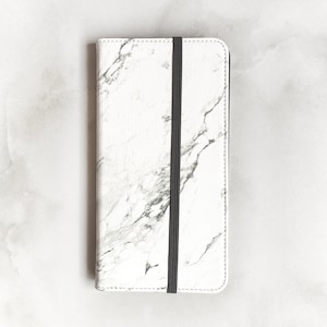May include: A white marble-patterned notebook with a black elastic band closure.