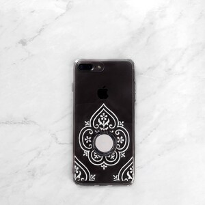 May include: A black phone case with a white intricate design and a silver ring holder.