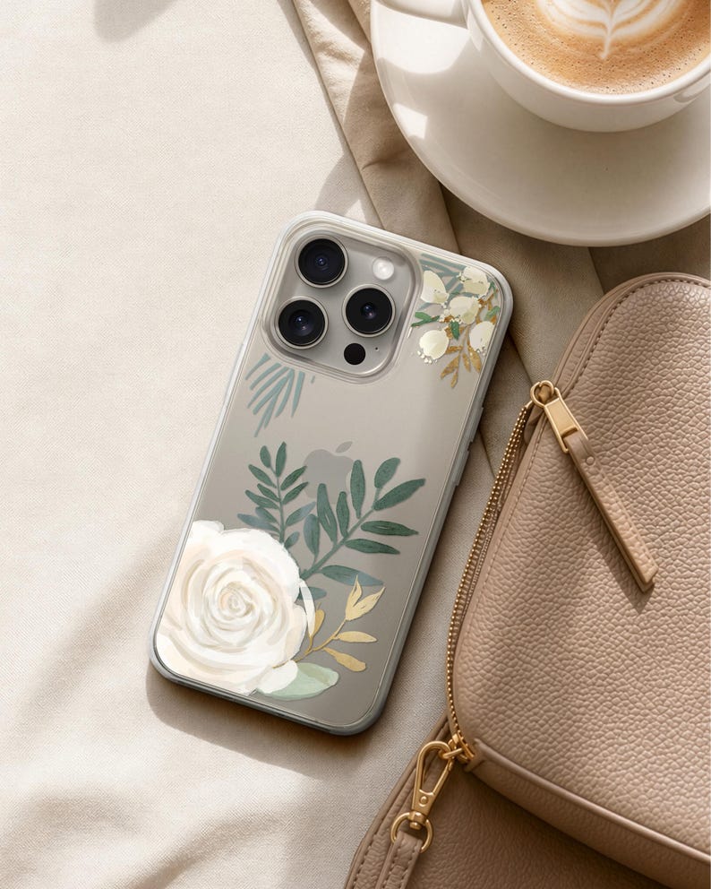 A smartphone with a floral design on its case, a cup of coffee, and a leather handbag are arranged on a beige surface.