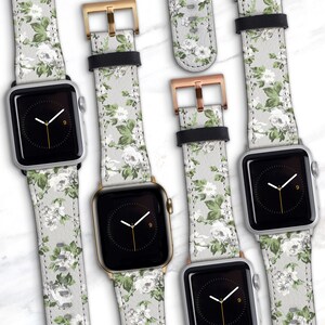 May include: Four Apple Watch bands with a floral pattern. The bands are in different colors, including silver, gold, and rose gold. The bands are made of leather and have a white background with green and white flowers.
