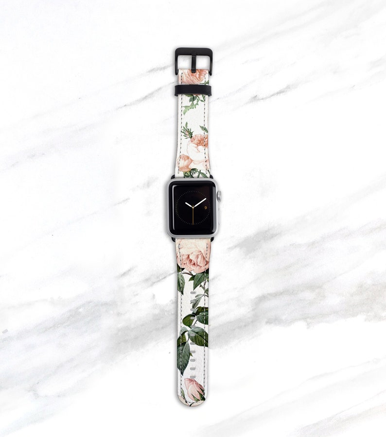 Op de afbeelding: Een wit Apple Watch bandje met een bloemenpatroon met roze rozen en groene bladeren.