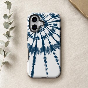 a white phone case with a tie-dye pattern on it, placed on a beige surface next to some greenery.