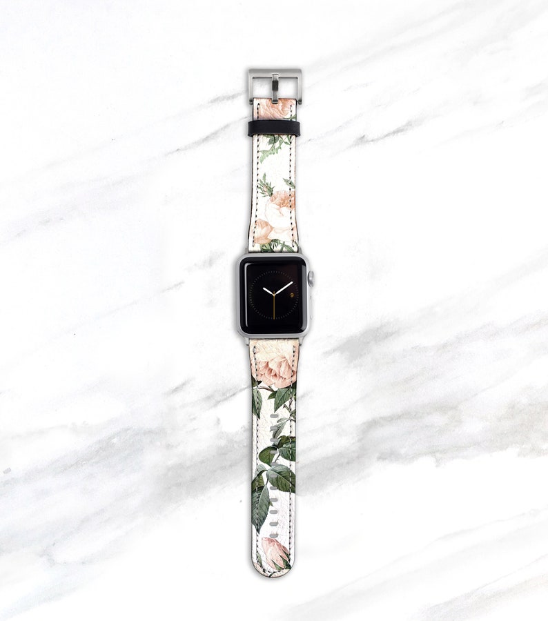 Op de afbeelding: Een witte Apple Watch met een band met bloemenprint. De band heeft roze en groene rozen en bladeren.