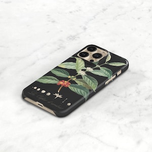 espresso phone cover for iPhone 16 Pro. A black phone case with a floral design. The design features a branch of coffee beans with green leaves and white flowers.