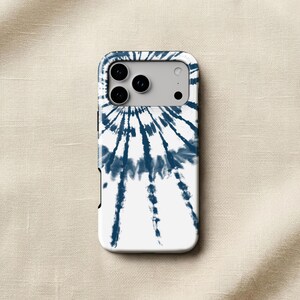a white phone case with a tie-dye design on it, placed on a beige fabric background.