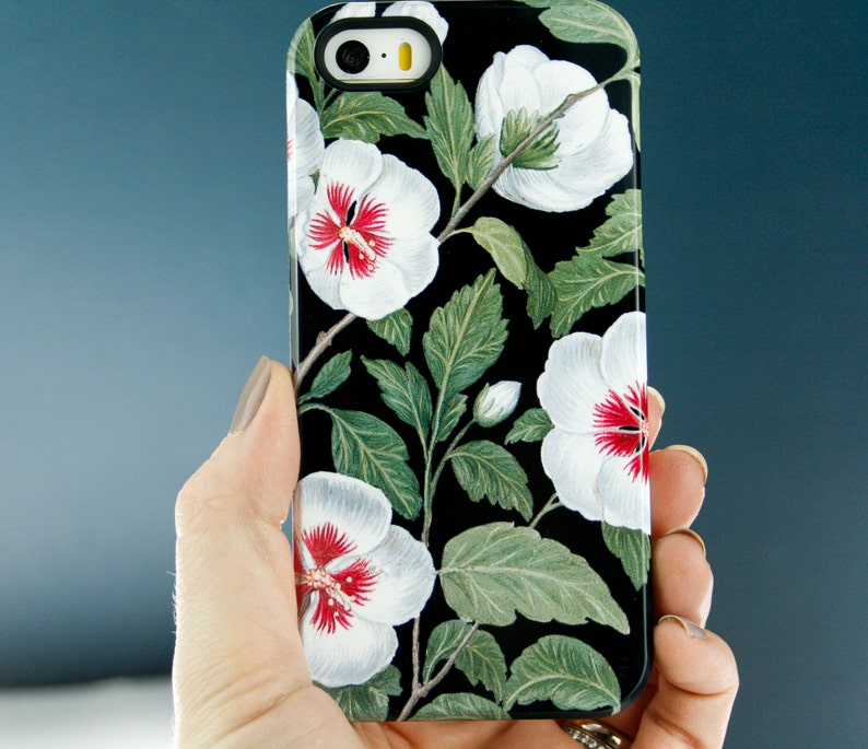 May include: A black phone case with a white hibiscus flower pattern. The flowers have red centers and green leaves.