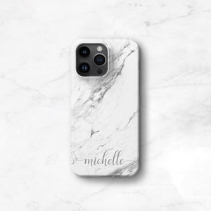 May include: White marble phone case with a black camera lens and the name "michelle" written in cursive.