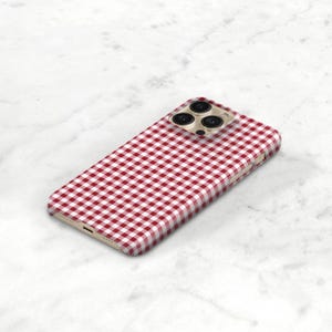 Pu&ograve; includere: Custodia per smartphone con motivo a quadretti rossi e bianchi. La custodia ha una protezione per l'obiettivo della fotocamera color oro e un design elegante. Progettata per adattarsi a uno smartphone, offre protezione e stile.
