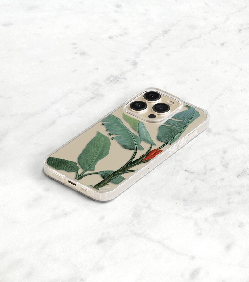 A clear phone case with a tropical leaf design. The case has a clear background with green leaves and a red flower. The case is designed for an iphone with a triple lens camera.