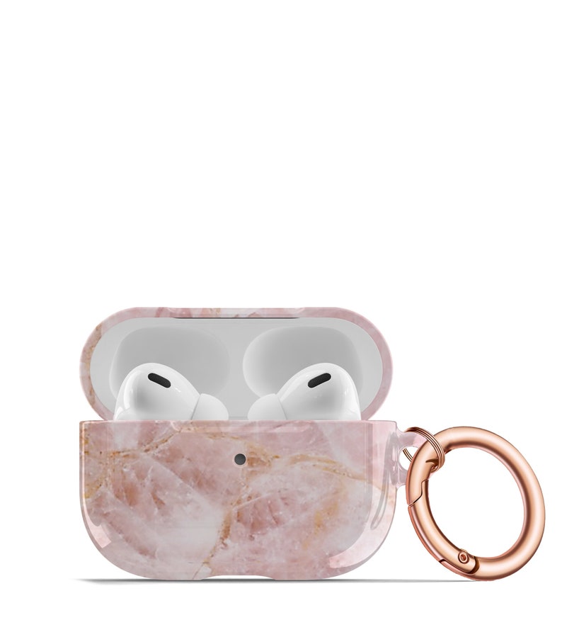 May include: A pink marble patterned case for Apple AirPods with a rose gold carabiner clip.