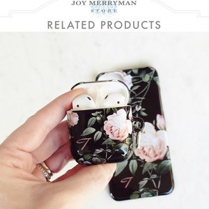 May include: A black phone case and a matching Airpods case with a floral design featuring pink roses and green leaves. The cases have a pink letter "J" on them.