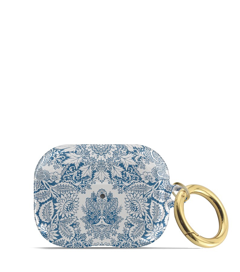 Peut inclure: Un &eacute;tui pour Airpods &agrave; motif bleu et blanc avec un anneau en m&eacute;tal dor&eacute;. L'&eacute;tui pr&eacute;sente un motif floral bleu et blanc.