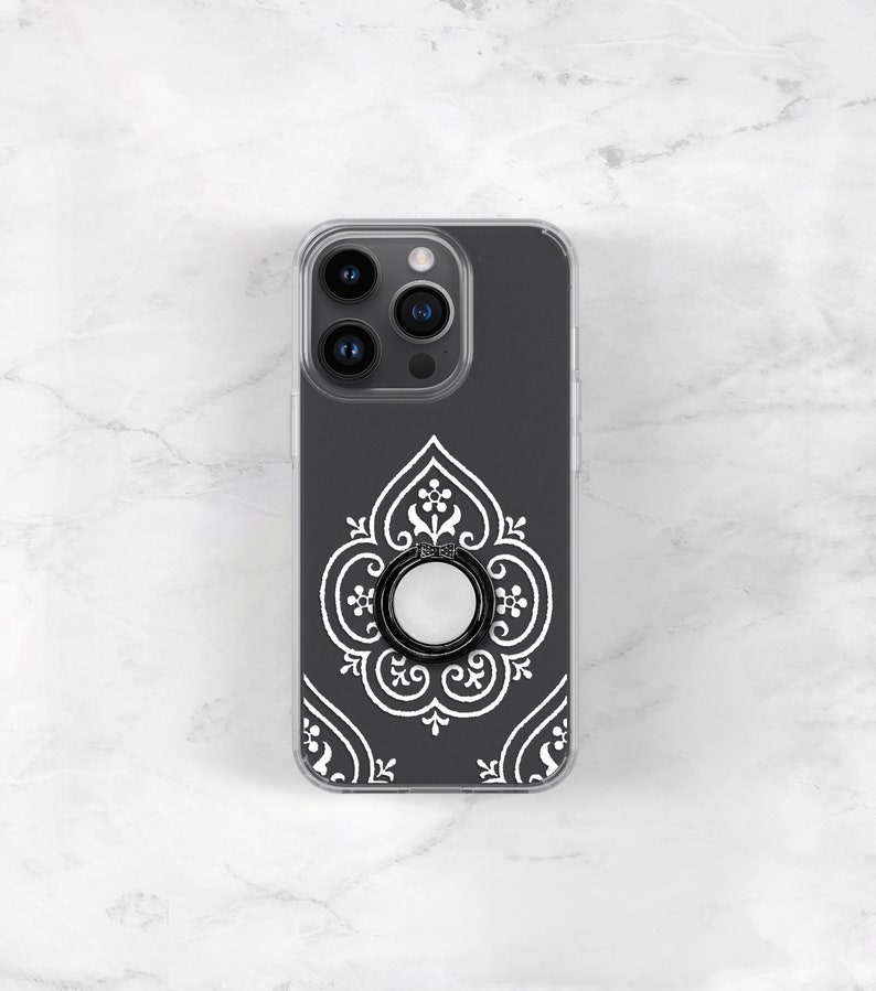 May include: A black phone case with a white intricate design and a black ring holder.