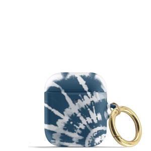 May include: A blue and white tie-dye patterned Airpods case with a gold metal ring attached.