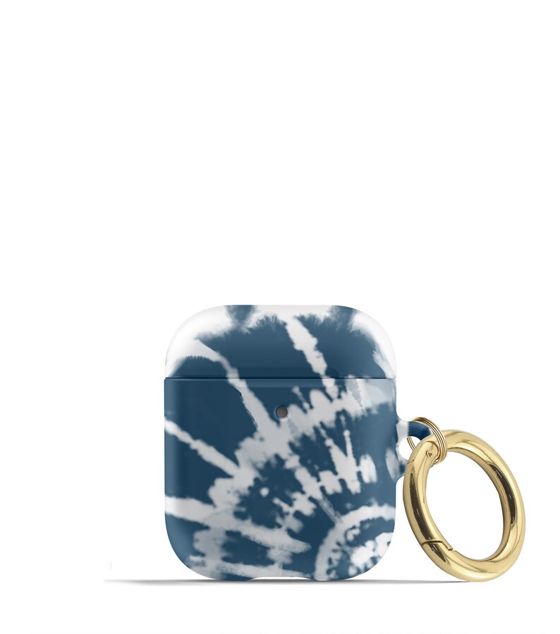 May include: A blue and white tie-dye patterned Airpods case with a gold metal ring attached.