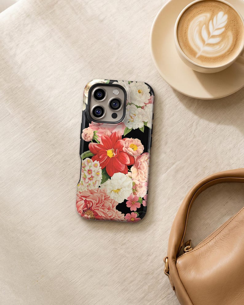 a floral phone case, a cup of coffee, and a purse on a table.