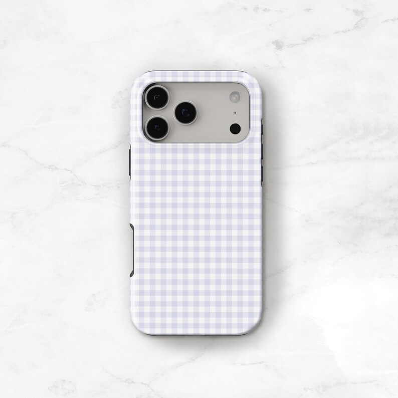 May include: A phone case with a light purple and white gingham pattern. The case has a rectangular shape with rounded corners and a camera cutout. The case is designed to fit a smartphone and protect it from scratches and damage.