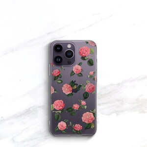 May include: A clear phone case with a floral design. The case features pink flowers with green leaves on a purple background.
