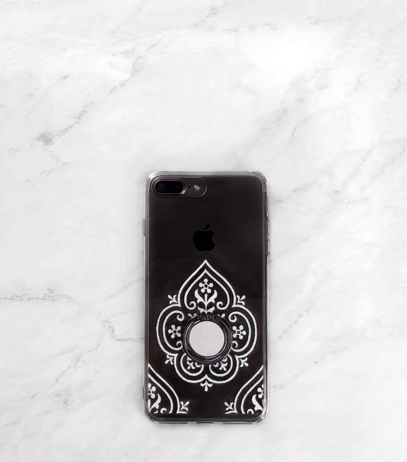 May include: A black phone case with a white intricate design and a silver ring holder.
