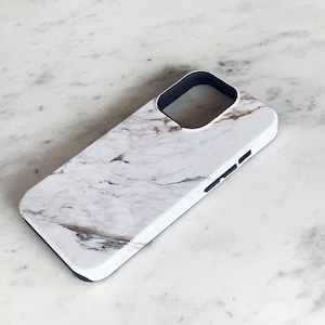 May include: White phone case with a marble pattern and a black camera cutout.