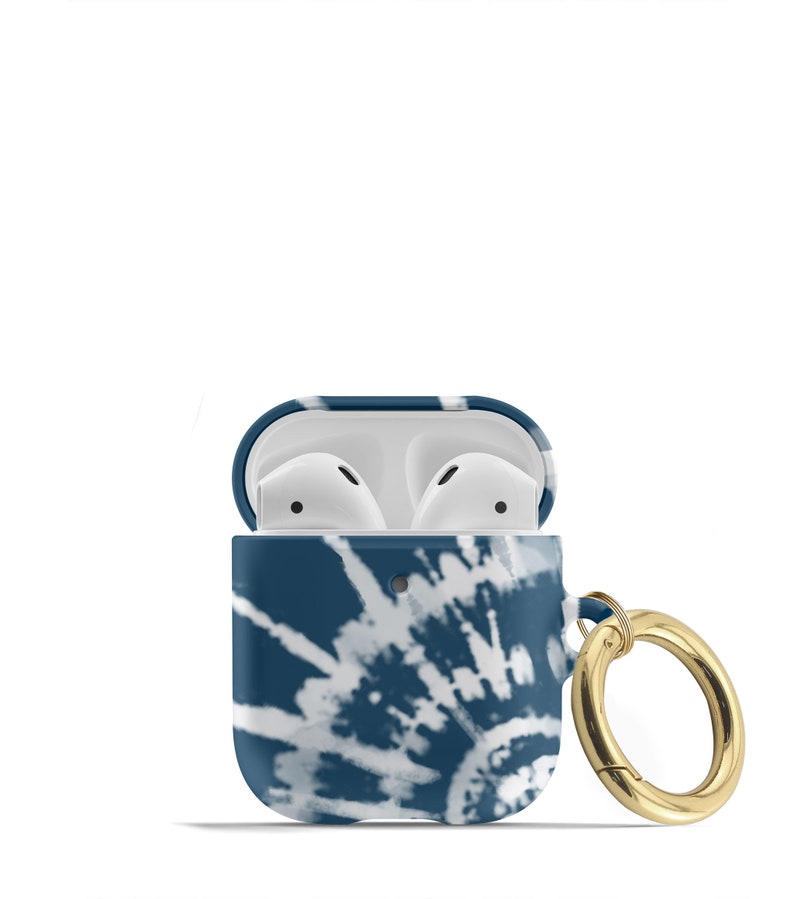 May include: A blue and white tie-dye patterned Airpods case with a gold metal ring attached. The case is open, revealing the white Airpods inside.