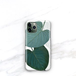 May include: A white phone case with a green leaf design. The leaves are detailed and realistic, with a light green color and dark green veins.