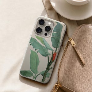 A smartphone with a leafy green and red plant design case, a beige purse, and a cup of coffee are arranged on a beige surface.