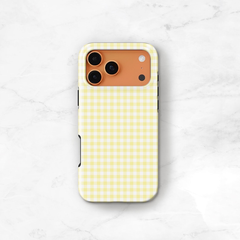 May include: A yellow and white gingham patterned phone case. The case has a square shape with rounded corners and a camera cutout. The phone case is designed to fit a smartphone and protect it from damage.