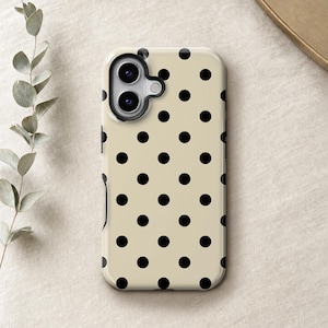 May include: A rectangular smartphone case featuring a light beige background with a repeating pattern of solid black polka dots. The case includes a black camera lens cutout area at the top left corner, designed to accommodate a dual-lens camera system.