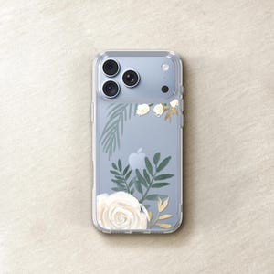 a clear iPhone case with a floral design featuring white roses and green leaves.