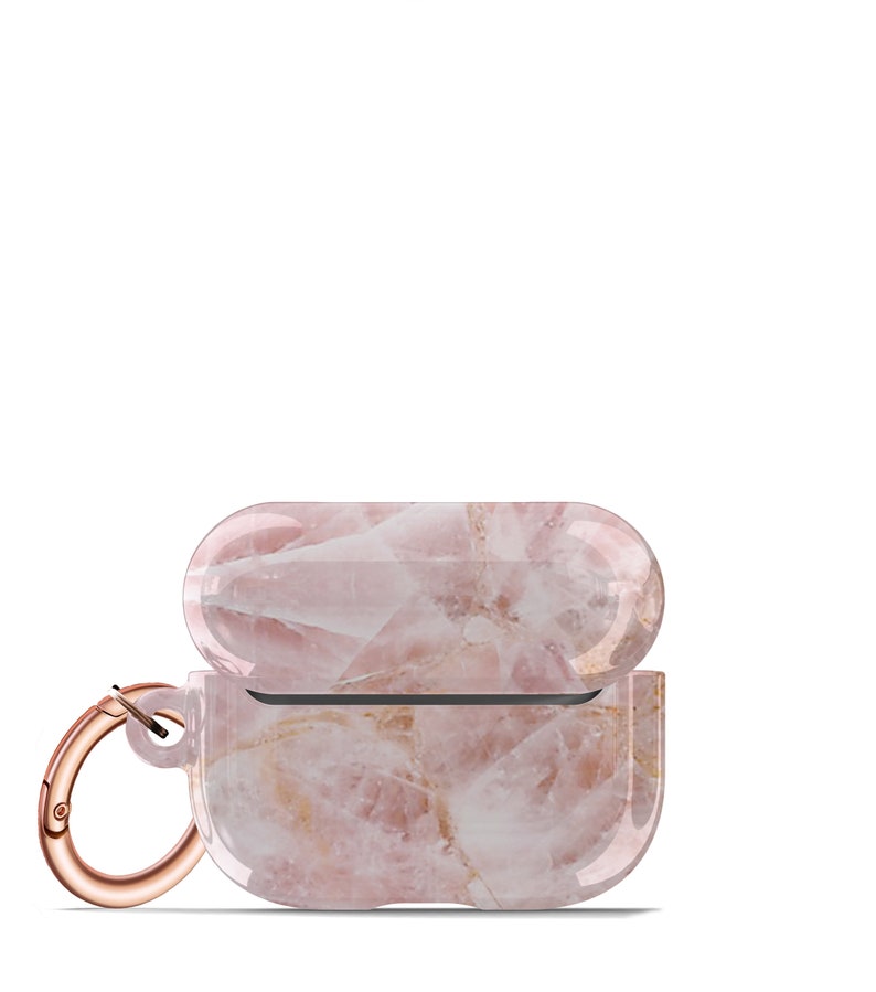 May include: A pink and white marble-patterned protective case for wireless earbuds with a rose gold carabiner clip.