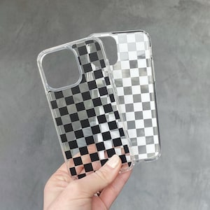 May include: Two clear protective phone cases featuring a black and white checkered pattern. Each case has a large square cutout for the camera module and precise openings for buttons and ports, showcasing a repeating grid design on the back.
