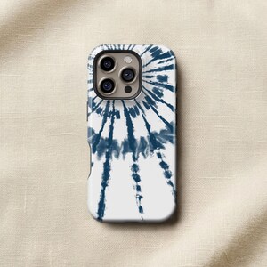 a white phone case with a tie-dye pattern on it, placed on a beige fabric background.