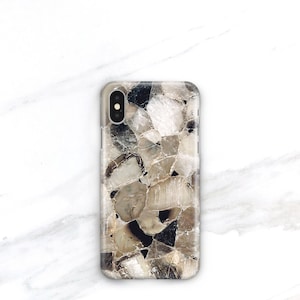 May include: A phone case with a brown and white abstract pattern. The pattern resembles a mosaic of small, irregular shapes.