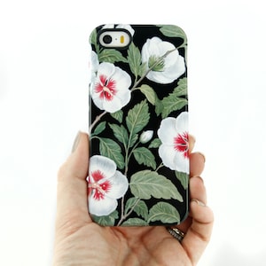 May include: Black phone case with a white floral design. The flowers have red centers and are arranged on a black background.