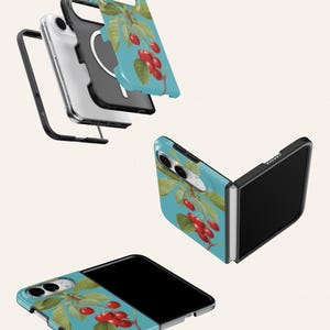 a collection of three smartphone cases, each with a unique design. The cases are predominantly blue and green in color, with a prominent design of cherries on the front. The cases appear to be made of a flexible material, suggesting they are designed to be worn over the phone's screen.
