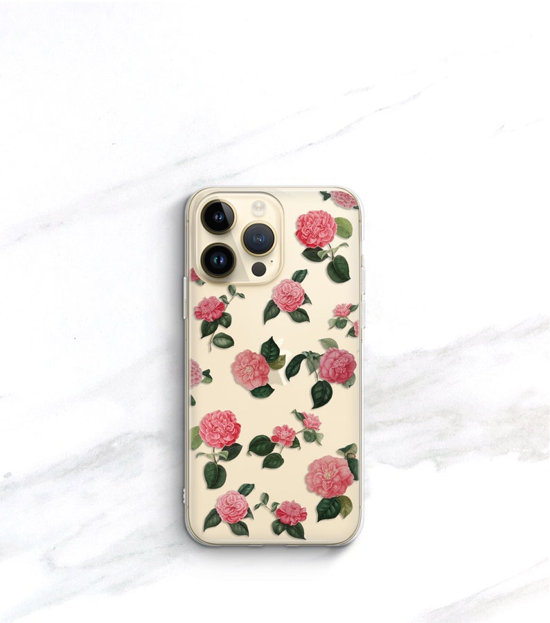 May include: A clear phone case with a floral design. The case features pink and white flowers with green leaves on a cream background.