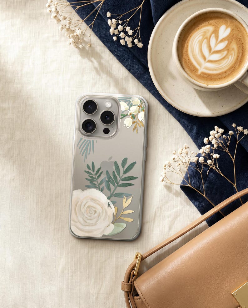 a smartphone with a floral design on its case, a cup of coffee, a purse, and some white flowers.