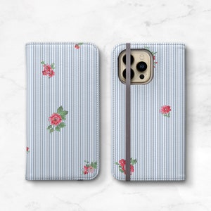 May include: A blue and white striped phone case with a floral pattern and a brown strap. The case has a cutout for the phone's camera.